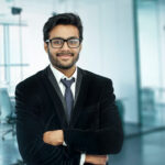 Businessman portrait. Happy confident young businessman standing arms crossed, smiling, looking at camera.